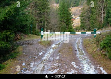 View from a Spruce Fir Forest to a Mountain Village through an Ecological Barrier on a Dirt Road. Limit Vehicle Access in a National Nature Park. Stock Photo