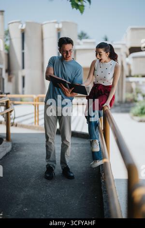 Two cheerful students reviewing documents outdoors during a pleasant day Stock Photo