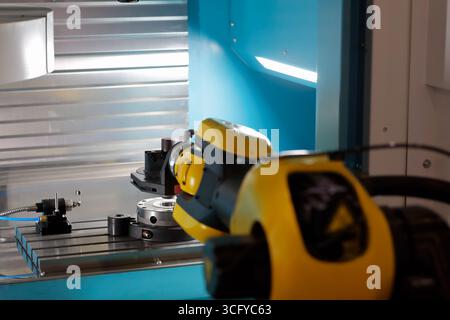 CNC machine automation with robotic arm. Automation of loading parts into CNC machine with industrial robotic arm manipulator. Selective focus. Stock Photo