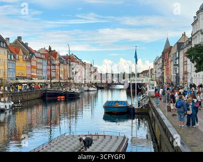 Nyhavn, Copenhagen, Denmark - 2 August 2025: Charming canal lined with vibrant buildings, boats, and outdoor seating in Copenhagen. Stock Photo