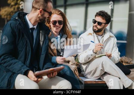 Three professionals collaborating and discussing documents while sitting outside Stock Photo