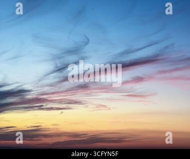 Magical sky during sunset with vivid hues and soft clouds glowing in warm evening light, ideal for backgrounds or design. Stock Photo