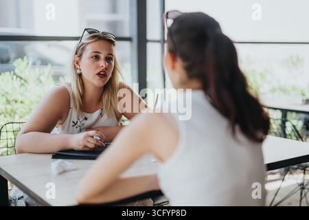 Two women having a discussion at a cafe, engaging in meaningful conversation Stock Photo