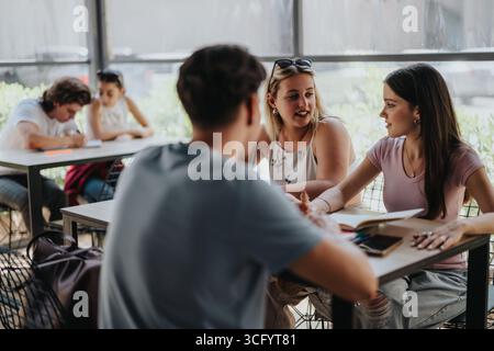 Diverse students collaborating at a study table with open notebooks Stock Photo