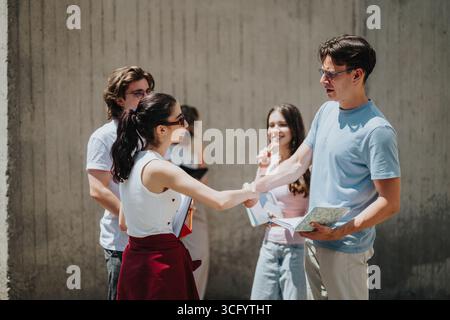 Group of students interacting and shaking hands outdoors on a sunny day Stock Photo