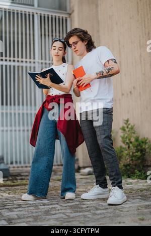 Two young adults collaborating while reviewing notes outdoors Stock Photo