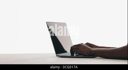 Close-up view of hands typing on a sleek modern laptop placed on a flat surface. Stock Photo