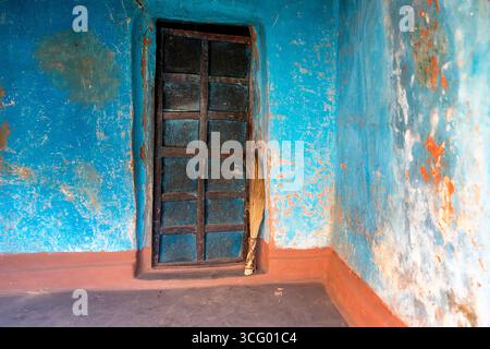 Beautiful traditional house made from mud in blue colour and beautiful rustic old handmade wooden door with a basic traditional broom in orissa, india Stock Photo