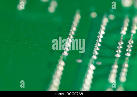 green and old circuit board with contacts, a simple green printed circuit board with an electronic circuit with soldered elements Stock Photo