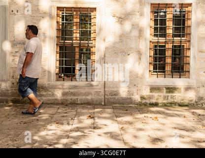 Older man casually walking near a traditional turkish stone wall Stock Photo