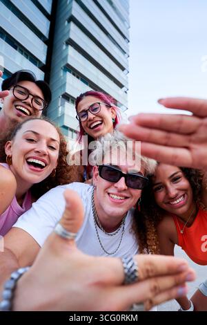Group of happy young friends taking a selfie, gesturing at the camera. Stock Photo