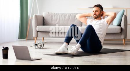 Smiling man working on abs, using laptop Stock Photo