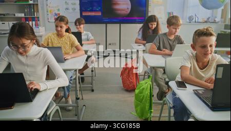Primary School Students Working on Creative Projects on Laptops, Practicing Digital Skills in Art Class. Digital Screen Showing AI Software for Creating Pictures. Interactive STEM Learning. Dolly Shot Stock Photo