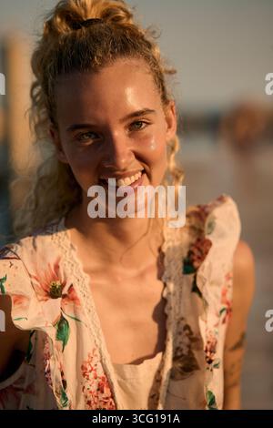 Blonde woman smiling at golden hour on beach Stock Photo