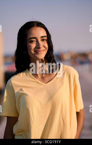 Young woman smiling at beach during golden hour Stock Photo