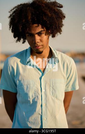 Young man with afro hair looking confident at sunset Stock Photo