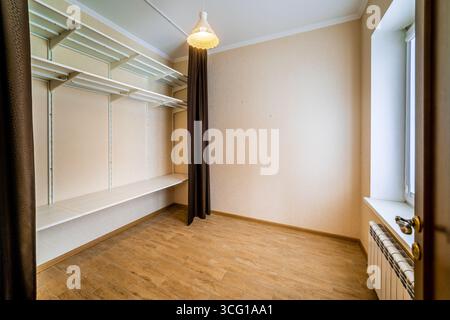 A small room with a white shelf and a brown curtain. The room is empty and has a simple design Stock Photo