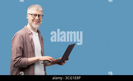 Working with joy. Young albino man using laptop and looking with smile to camera over turquoise studio background Stock Photo