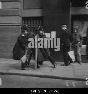 Two police officers lead a woman demonstrator away during a counter-demonstration against an anti-abortion rally, Oxford Road, Manchester, early 1970s.. Another demonstrator  with a placard, stands looking on. Stock Photo