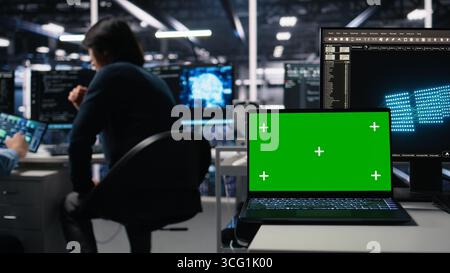 Close up of mockup laptop in server room where worker uses AI to review diagnostics. Admin in data center analyzing performance data using artificial intelligence on isolated screen notebook, camera A Stock Photo