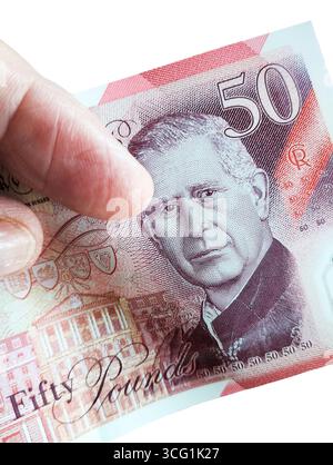 A King Charles Fifty pound note being held in hand against a white background. Stock Photo