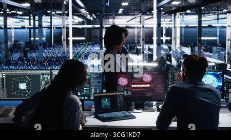 Engineers in AI server hub alerted by hacking incident involving theft of sensitive data. Teamworking data center employees alarmed by computer virus triggered by security systems, camera A Stock Photo