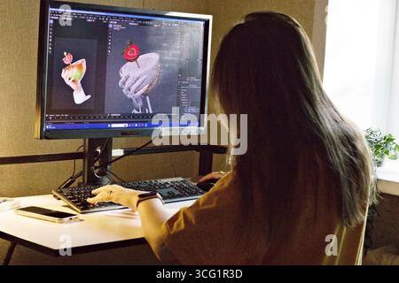 Young woman working on computer with 3D dessert model on screen, symbolizing creativity, digital design, and modern workflow in computer graphics, 3D Stock Photo