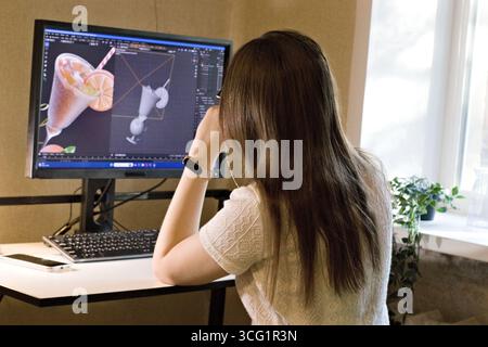 Young woman working on computer with 3D dessert model on screen, symbolizing creativity, digital design, and modern workflow in computer graphics, 3D Stock Photo