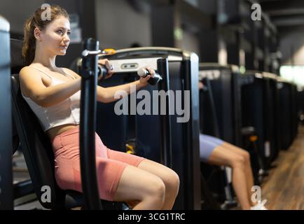 Woman doing arm exercise in machine Stock Photo