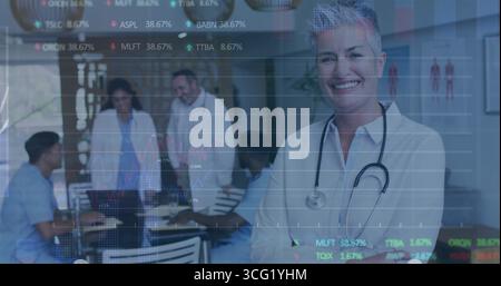 Smiling senior female doctor leading meeting in hospital room, with stethoscope, laptop, copy space Stock Photo
