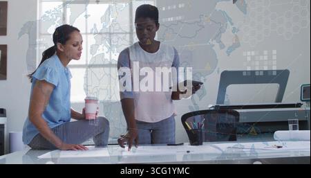 Collaborating two architects in business attire reviewing blueprints at drafting table, with tablet Stock Photo