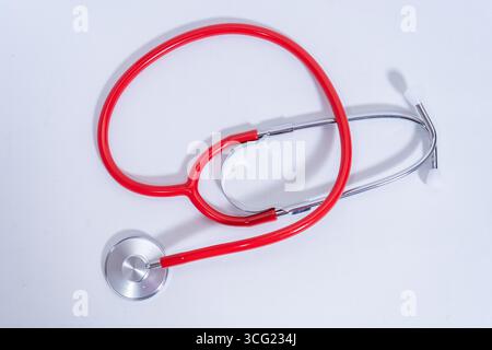 Red stethoscope on a white table representing healthcare and medical services Stock Photo