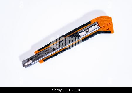 Used orange and black utility knife resting on a clean white background Stock Photo