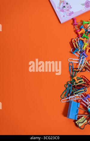 Office supplies creating a colorful border on a vibrant orange background, offering ample copy space for text or design elements Stock Photo