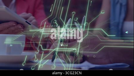 Collaborating three team members in office with tablet, pen, smartphone, neon green circuit overlay Stock Photo