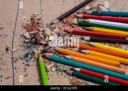 Colorful pencil shavings scattered around colored pencils on a cardboard surface Stock Photo
