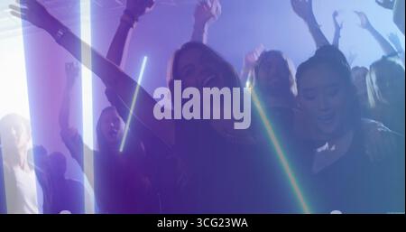 Center dancer wearing sleeveless top dancing in nightclub under LED bars, with spotlights and haze Stock Photo