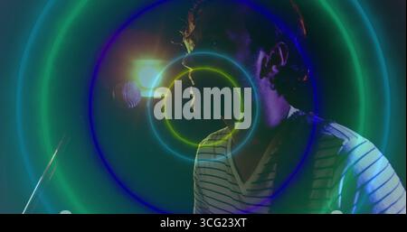 Singing musician wearing V-neck shirt on stage, with mic, backlight and neon rings, copy space Stock Photo
