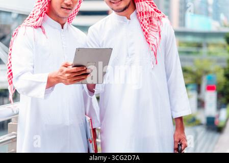 Arab team hold digital tablet uae union teamwork people. Digital marketing arab group of people using smart tablet discuss modern muslim UAE city. Ent Stock Photo