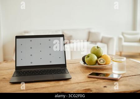 Modern Laptop Displaying Calibration Screen on Table Beside Fruit and Smartphone Stock Photo