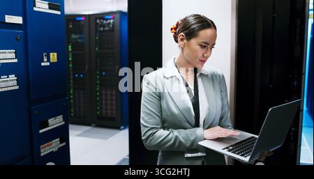 Laptop, typing and woman in data center for cybersecurity, network maintenance or programming. Administration, computer and firewall installation with Stock Photo
