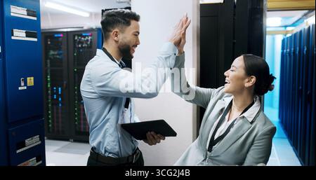 Man, woman and high five with smile in server room, success and team with IT solution at company. People, programmer and celebration with tablet Stock Photo