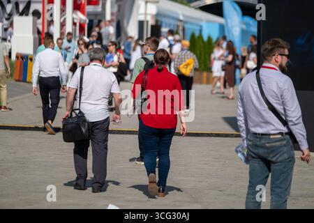 Crowd of people walking outdoors during a business event on a clear sunny day. Stock Photo