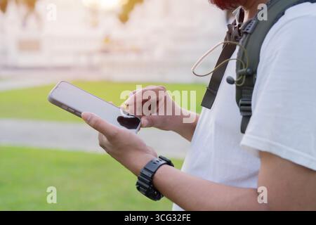 Shot of a handsome young man with backpack standing alone and using his cellphone. Selective focus. Stock Photo