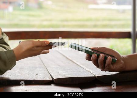 Side view of two young people using mobile phones for internet online with happy feeling at outdoors. Stock Photo