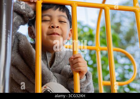 Kid exercise for health and sport concept. Happy Asian child boy playing at the playground. Happy kids face concept. Stock Photo