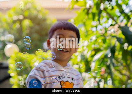 Child and Soap Bubbles Concept. Happy child blowing bubbles in park. Selective focus. Stock Photo