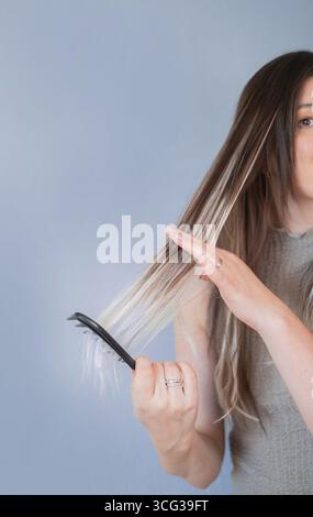 Young woman gently combing hair extensions showing comfort and ease of hair care in professional beauty salon Stock Photo