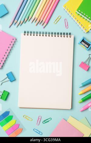 Notepad, markers, pens and other supply. Flat lay image on blue background. Stock Photo