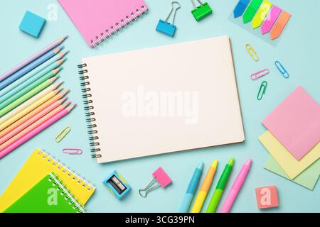 Notepad, markers, pens and other supply. Flat lay image on blue background. Stock Photo